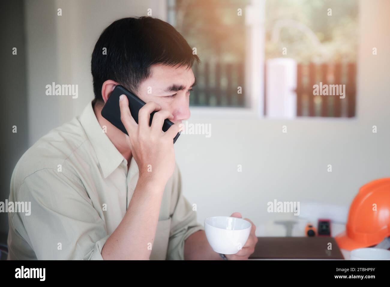Der junge Architekt telefoniert mit Kunden in seinem Home Office. Konzeptarbeit von zu Hause aus. Stockfoto