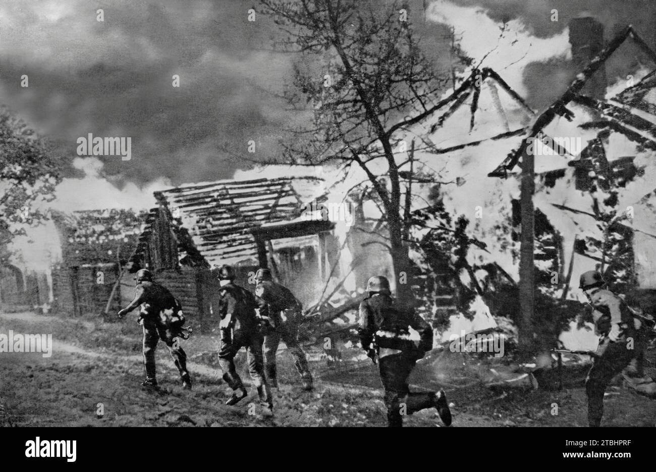 Soldaten der Wermacht, die im September 1941 während der deutschen Invasion Russlands im Zweiten Weltkrieg an einem brennenden russischen Dorf vorbeizogen. Stockfoto