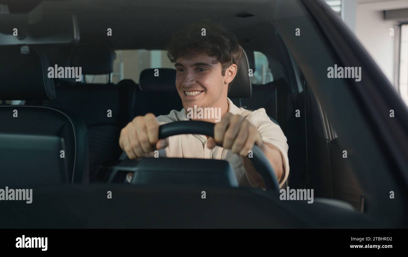 Kaukasischer glücklicher sorgloser, fröhlicher Mann Käufer Besitzer eines neuen Autos Mann erfolgreicher Geschäftsmann, der im Auto sitzt, feiert Auto Transport Fahrzeug Stockfoto