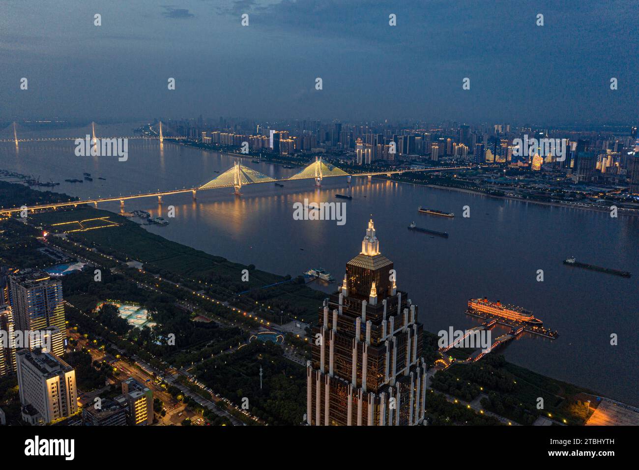 Ein atemberaubender Blick aus der Luft auf den Yangtze River, Wuhan erleuchtete mit Lichtern und Wolkenkratzer auf beiden Seiten begannen zu leuchten Stockfoto