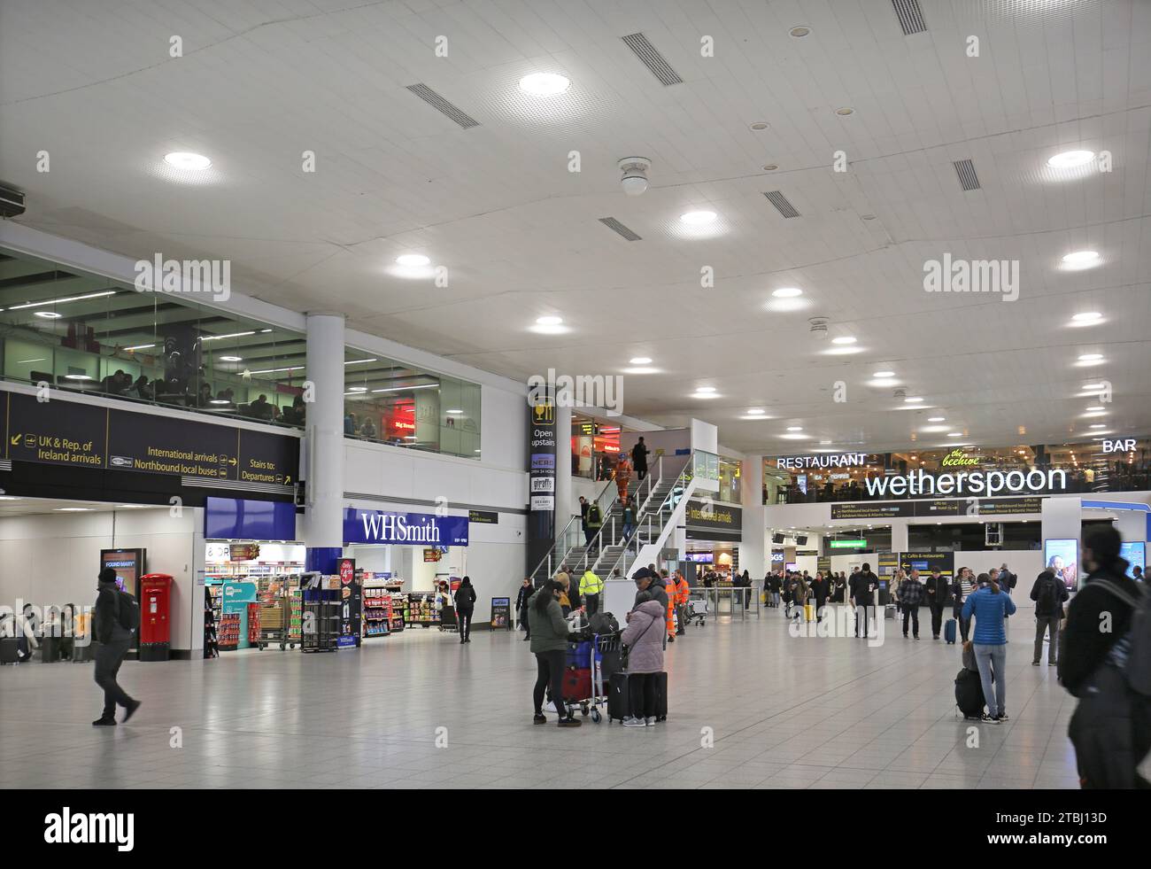 Flughafen Gatwick, Südterminal, Check-in-Bereich. Zeigt Passagiere, Abfahrtstafeln, Geschäfte und Restaurants. Stockfoto
