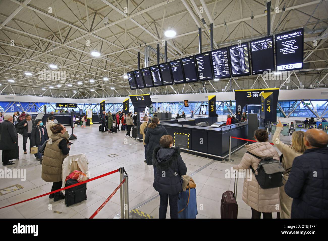 Die neu erweiterte Bahnhofshalle am Londoner Flughafen Gatwick, Großbritannien (Dezember 2023). Zeigt Infotafeln für die Zugabfahrt und den Auskunftsschalter. Stockfoto