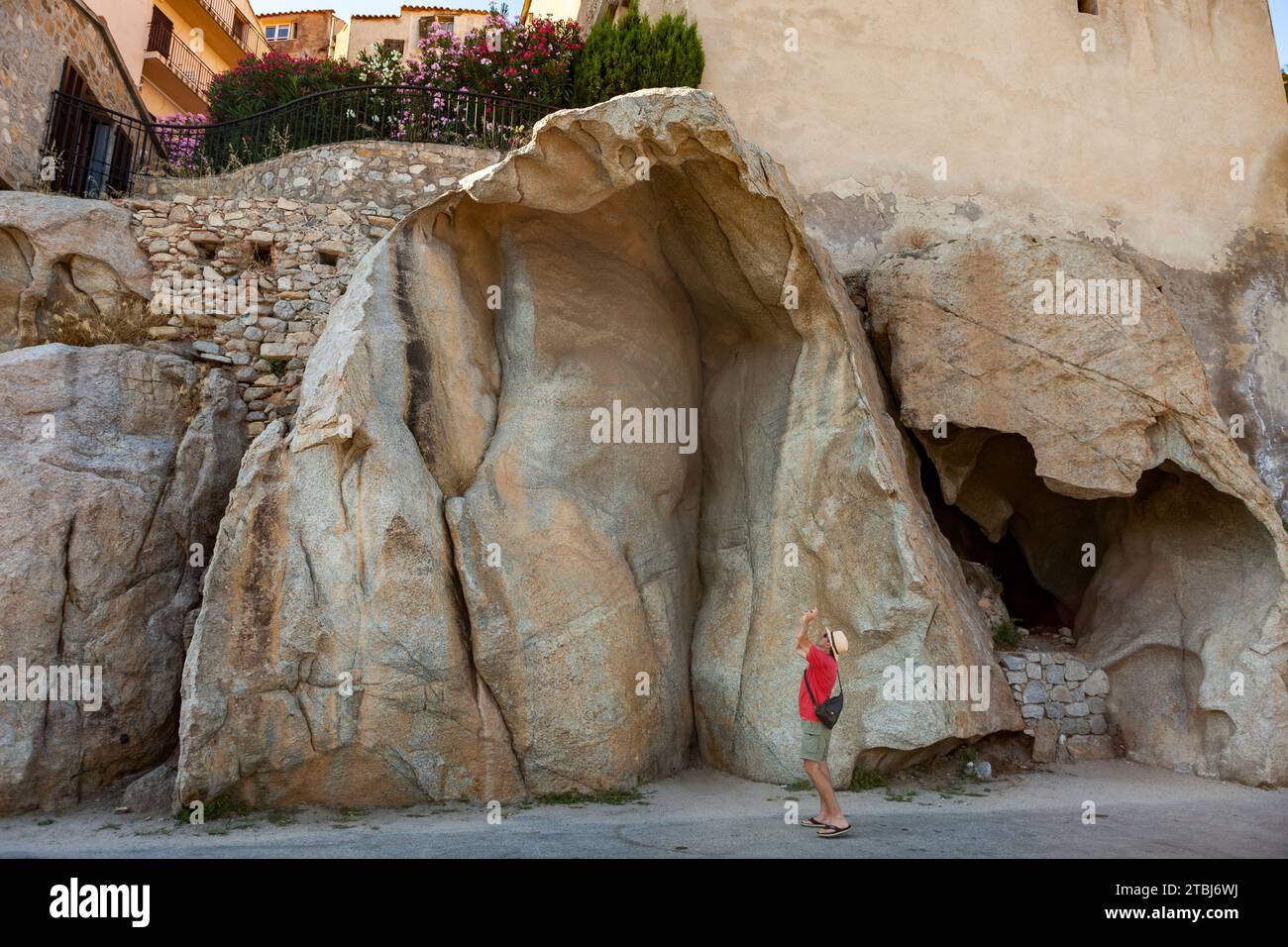 Ein Tourist fotografiert einen seltsam geformten Felsen in Calvi, Frankreich Stockfoto