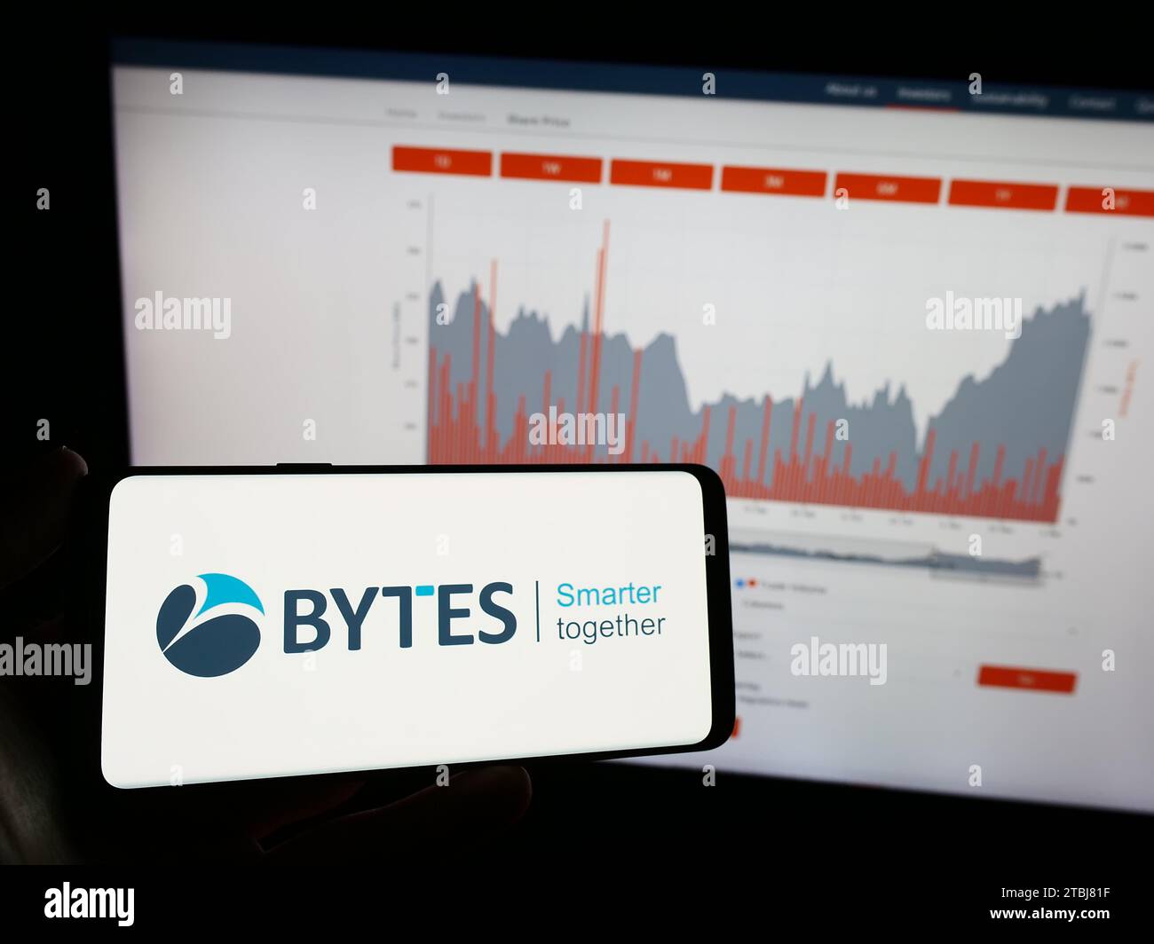 Person mit Mobiltelefon und Logo des britischen Softwareunternehmens Bytes Technology Group plc vor der Webseite. Schwerpunkt auf dem Display des Telefons. Stockfoto