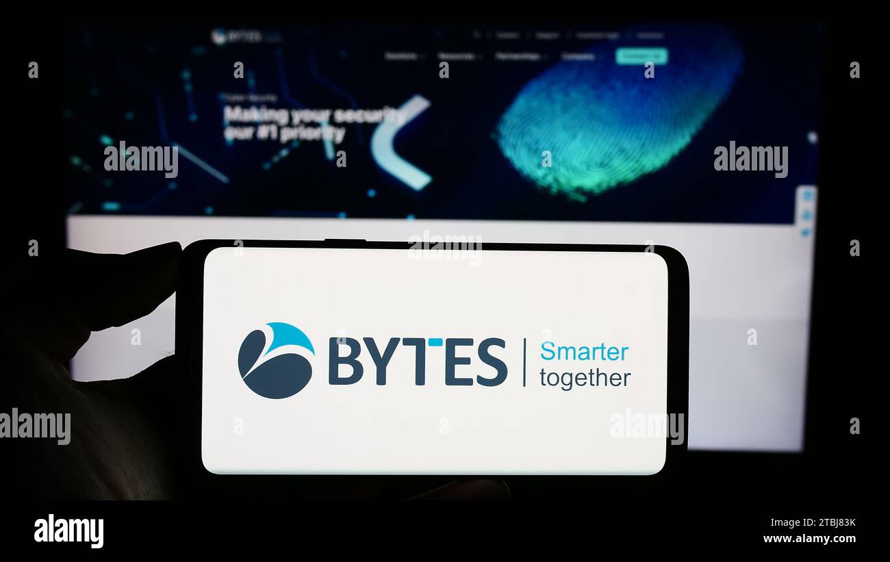 Person, die ein Mobiltelefon mit dem Logo des britischen Softwareunternehmens Bytes Technology Group plc vor der Business-Website hält. Schwerpunkt auf dem Display des Telefons. Stockfoto