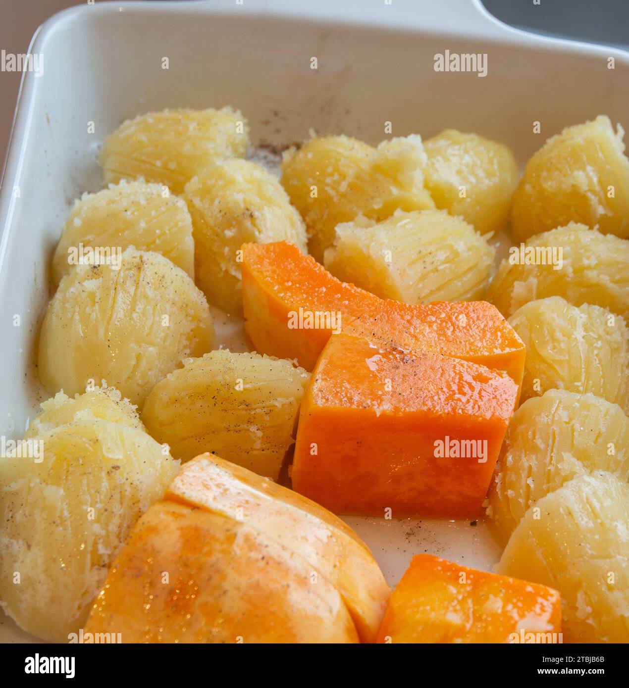 Kürbis und Kartoffeln in einer Ofenform braten und mit der Gabel knusprig schaben Stockfoto