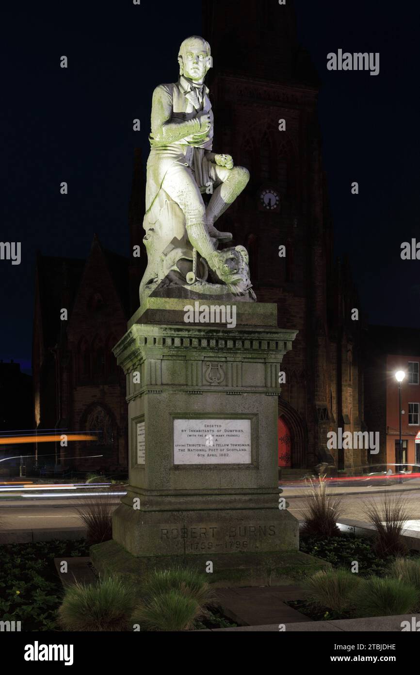 Die Statue des Dichters Robert Burns im Stadtzentrum von Dumfries, Greyfriars Church dahinter bei Nacht Schottland Großbritannien Stockfoto