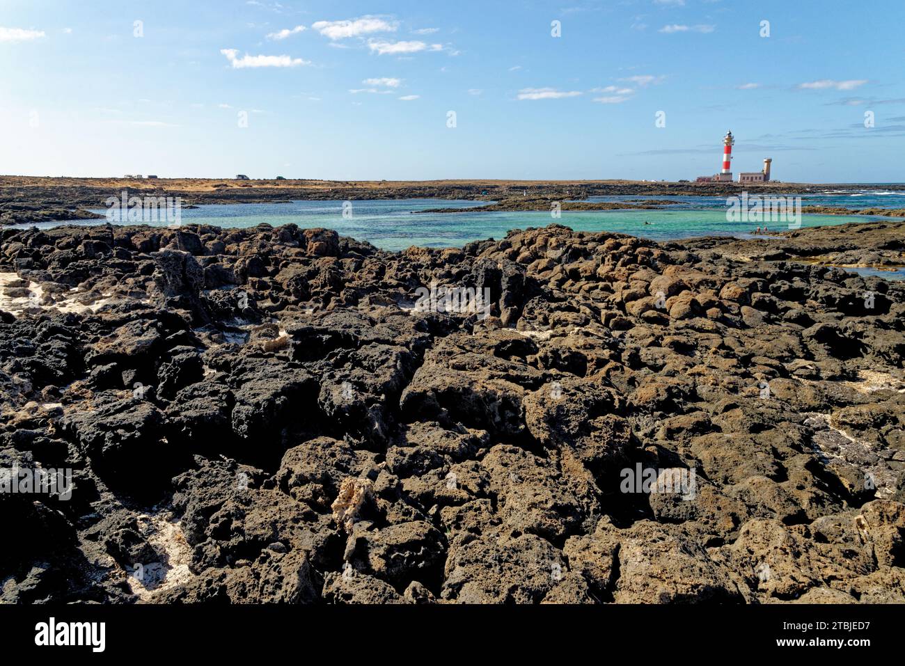 Natürliche Gezeitenbecken am Strand Playa de los Charcos und Leuchtturm von Toston - natürliche Pools am Strand von Los Laguitos oder Los Charcos auf Fuerteventura, Stockfoto