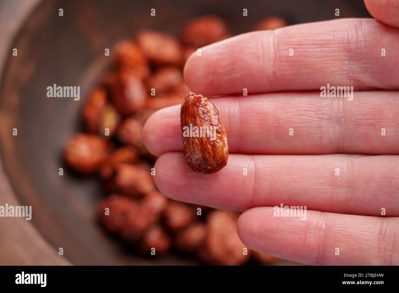 Süße kandierte Mandel in der Hand. Hausgemachte Leckereien aus Nüssen mit Zucker. Nahaufnahme Stockfoto