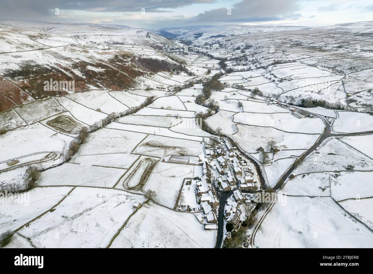 Blick hinunter auf einen schneebedeckten Swaledale im frühen Winter, mit dem Weiler Thwaite im Vordergrund und dem Fluss Swale, der sich den dale hinunter schlängelt. York Stockfoto