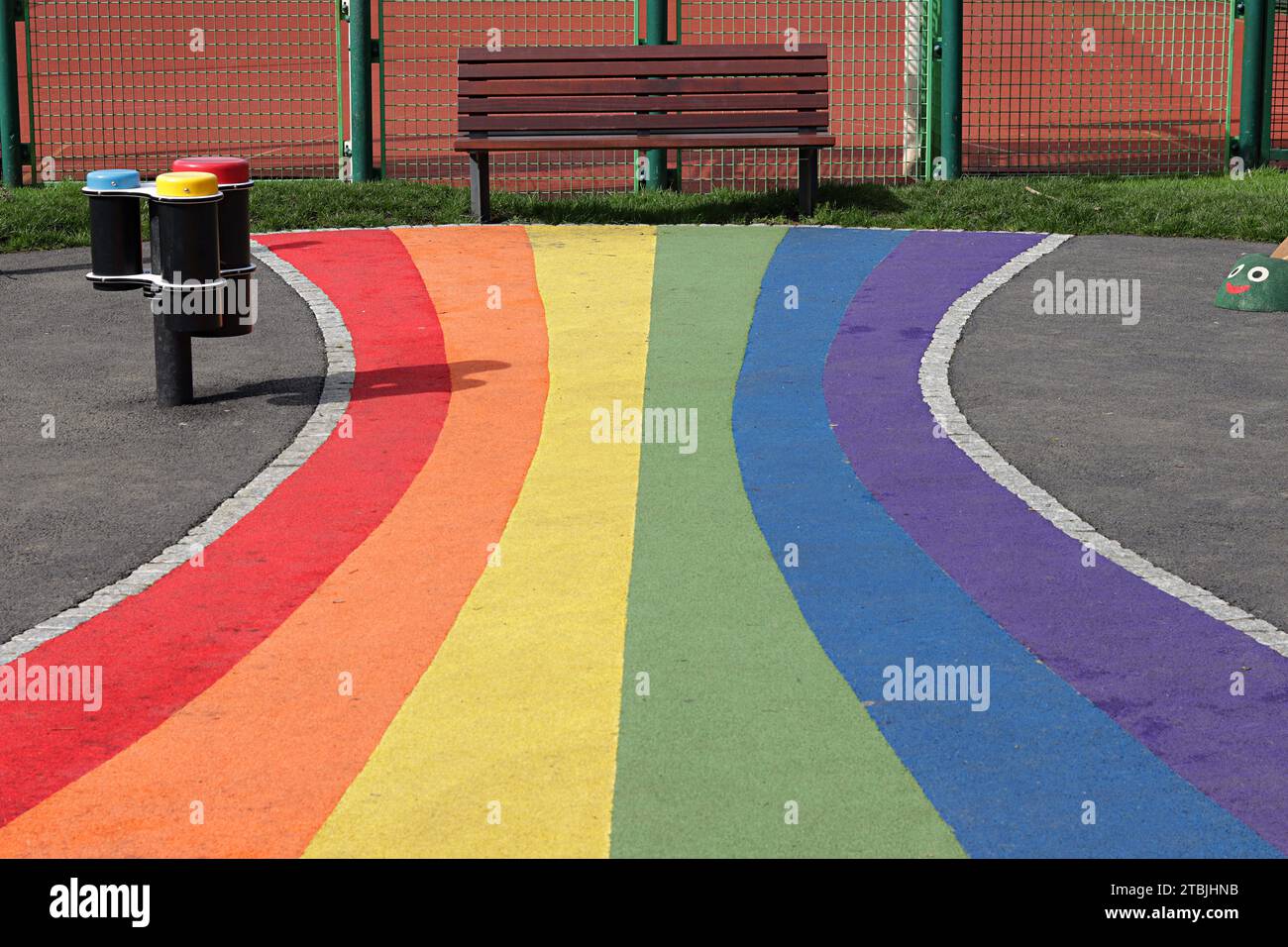 Spielplatz, farbenfroher Regenbogenpfad zu einer Bank in einem öffentlichen Garten. Stockfoto