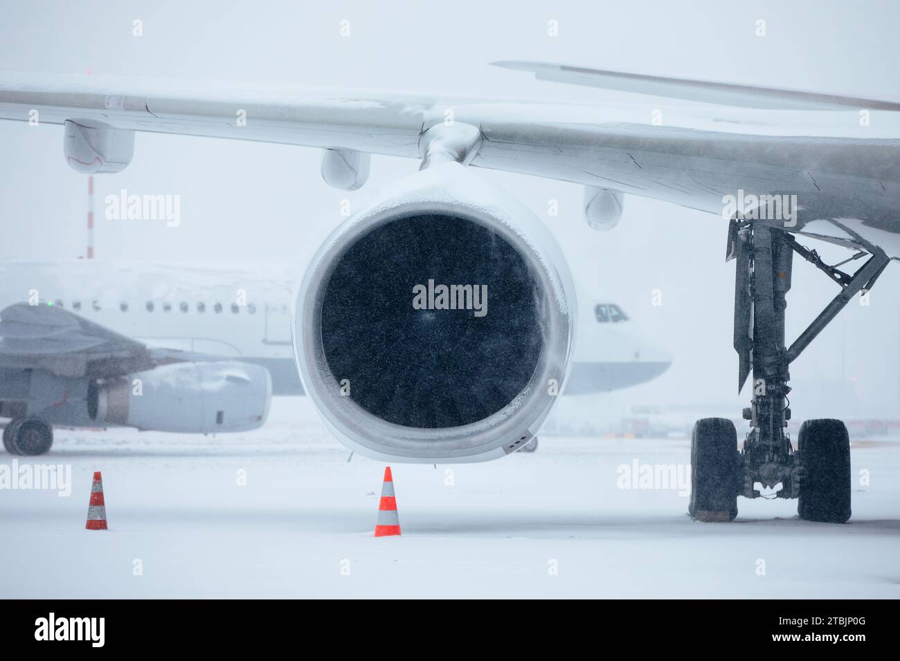 Verkehr am Flughafen bei starkem Schneefall. Schneeflocken gegen Düsentriebwerk und Rollflugzeug auf dem Rollweg des Flughafens an frostigen Wintertagen. Extremer Witterungseinfluss Stockfoto