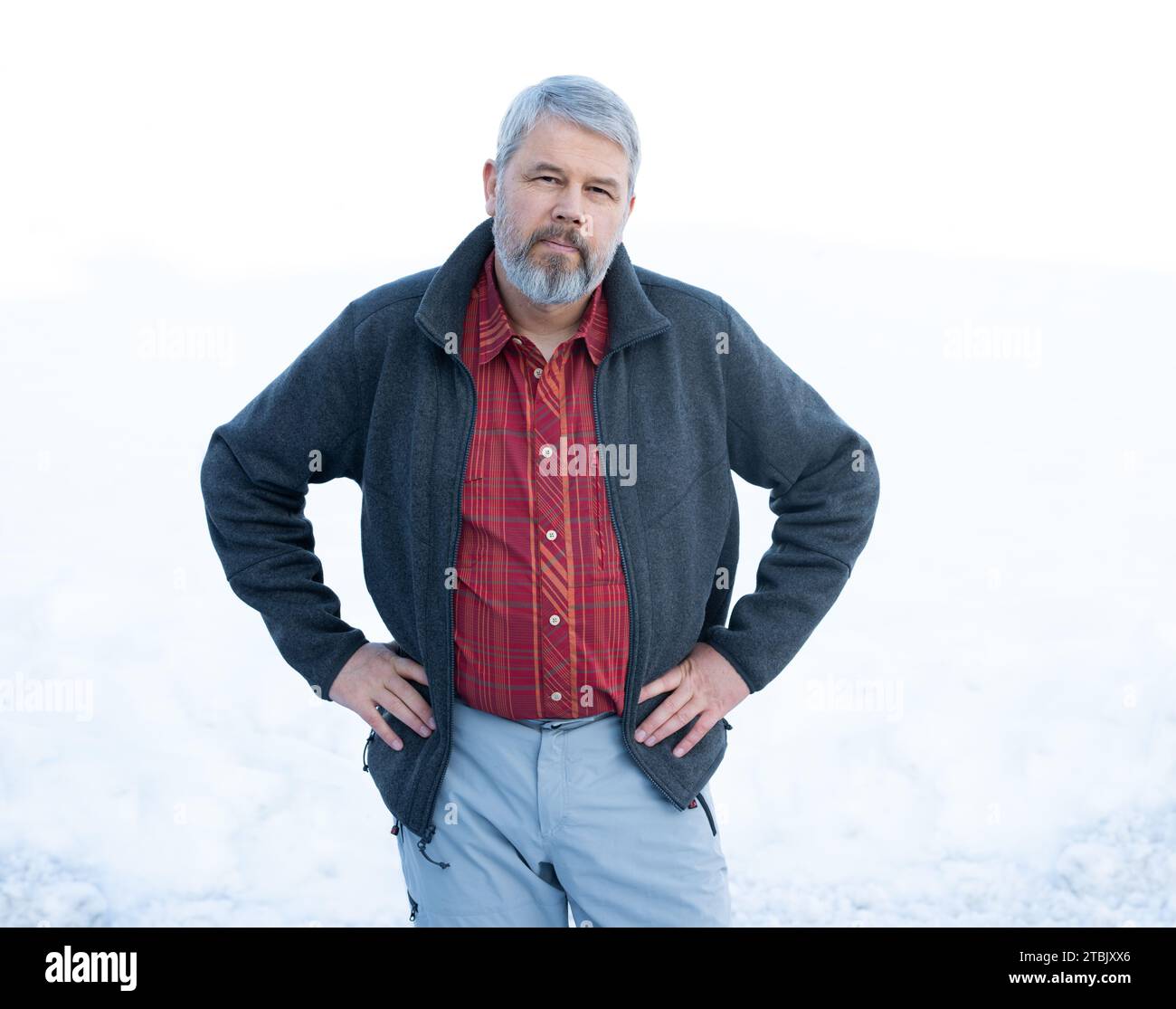 Mann, 56 Jahre, graues Haar und Bart, im Winter draußen stehend mit Schnee im Hintergrund, Stockfoto