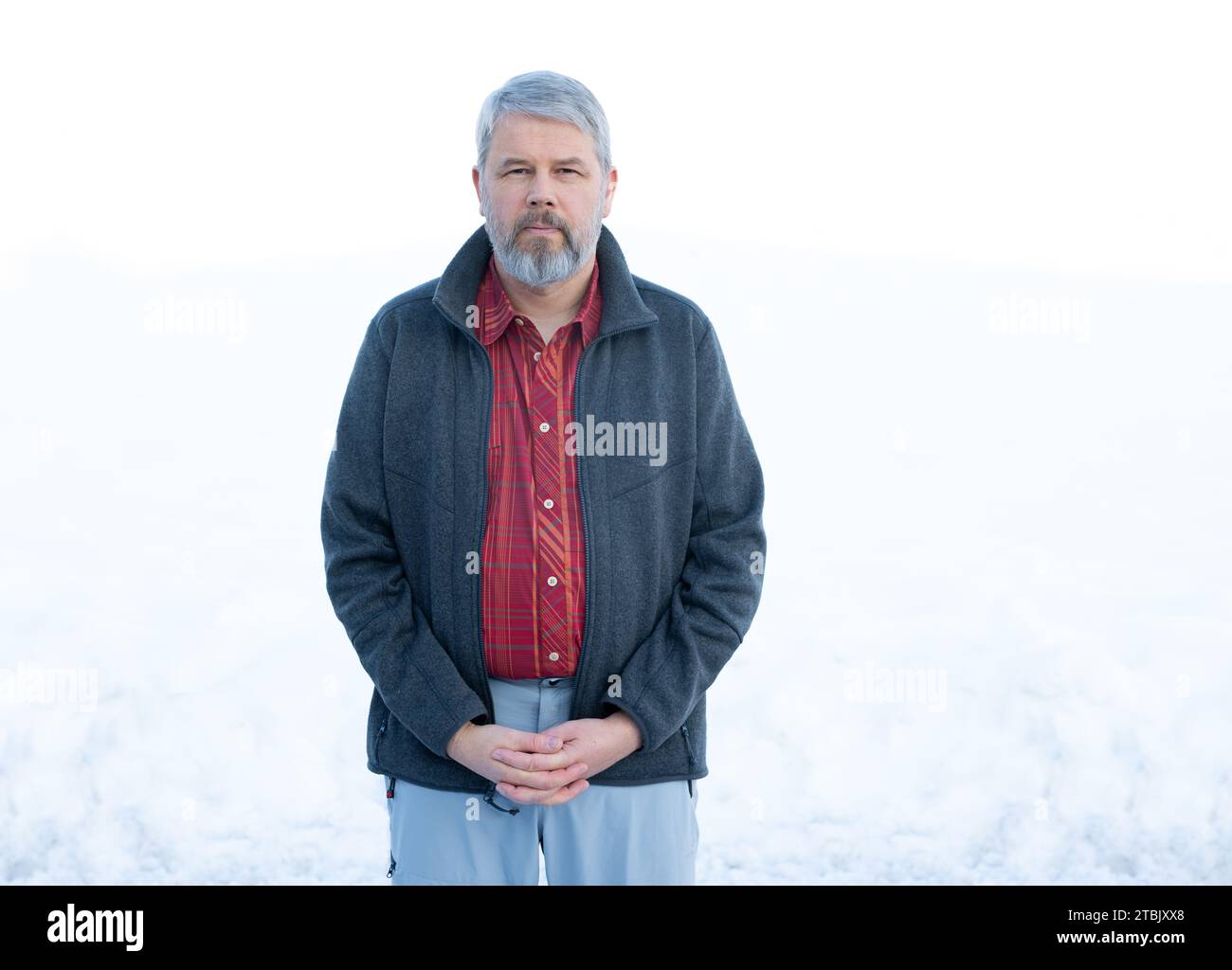 Mann, 56 Jahre, graues Haar und Bart, im Winter draußen stehend mit Schnee im Hintergrund, Stockfoto