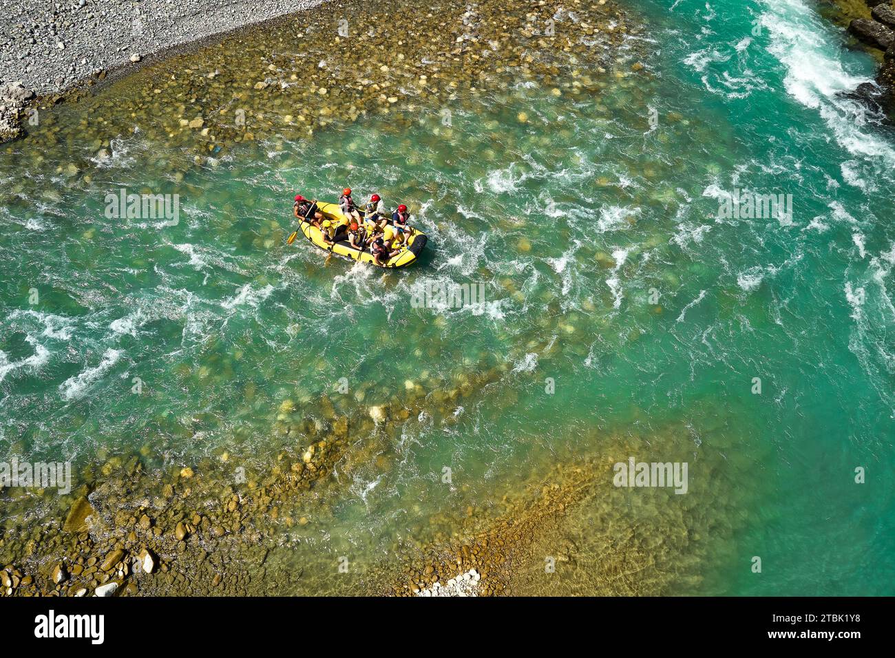 Wildwasser-Rafting. Abenteuer und Sport. Ein gelbes Floß, das auf dem kristallklaren, blau-grünen Wasser schwimmt. Senkrechte Drohnenansicht. Stockfoto
