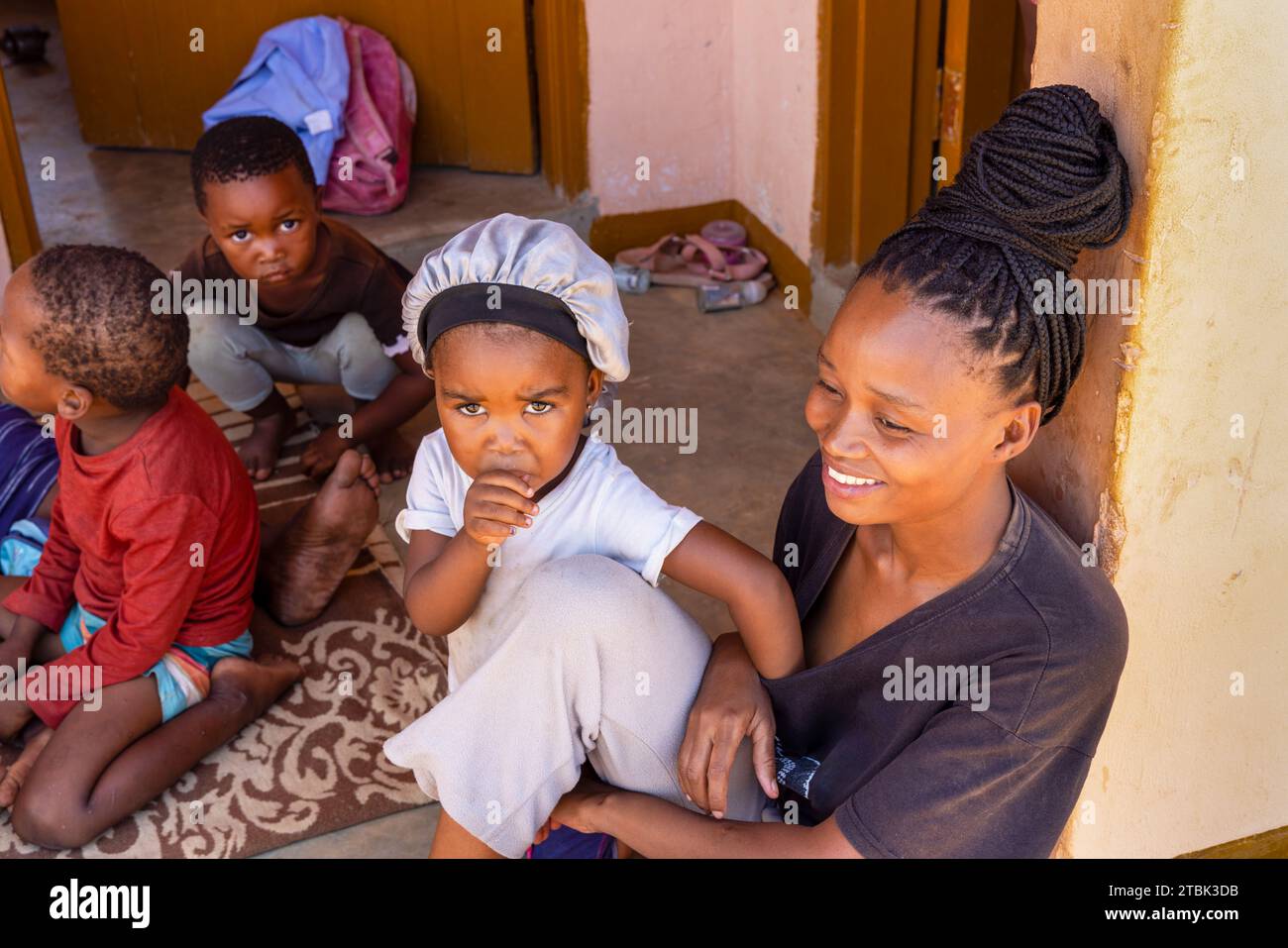 Dorf, afrikanische Familie sitzt vor dem Haus, Mutter mit Kindern Stockfoto