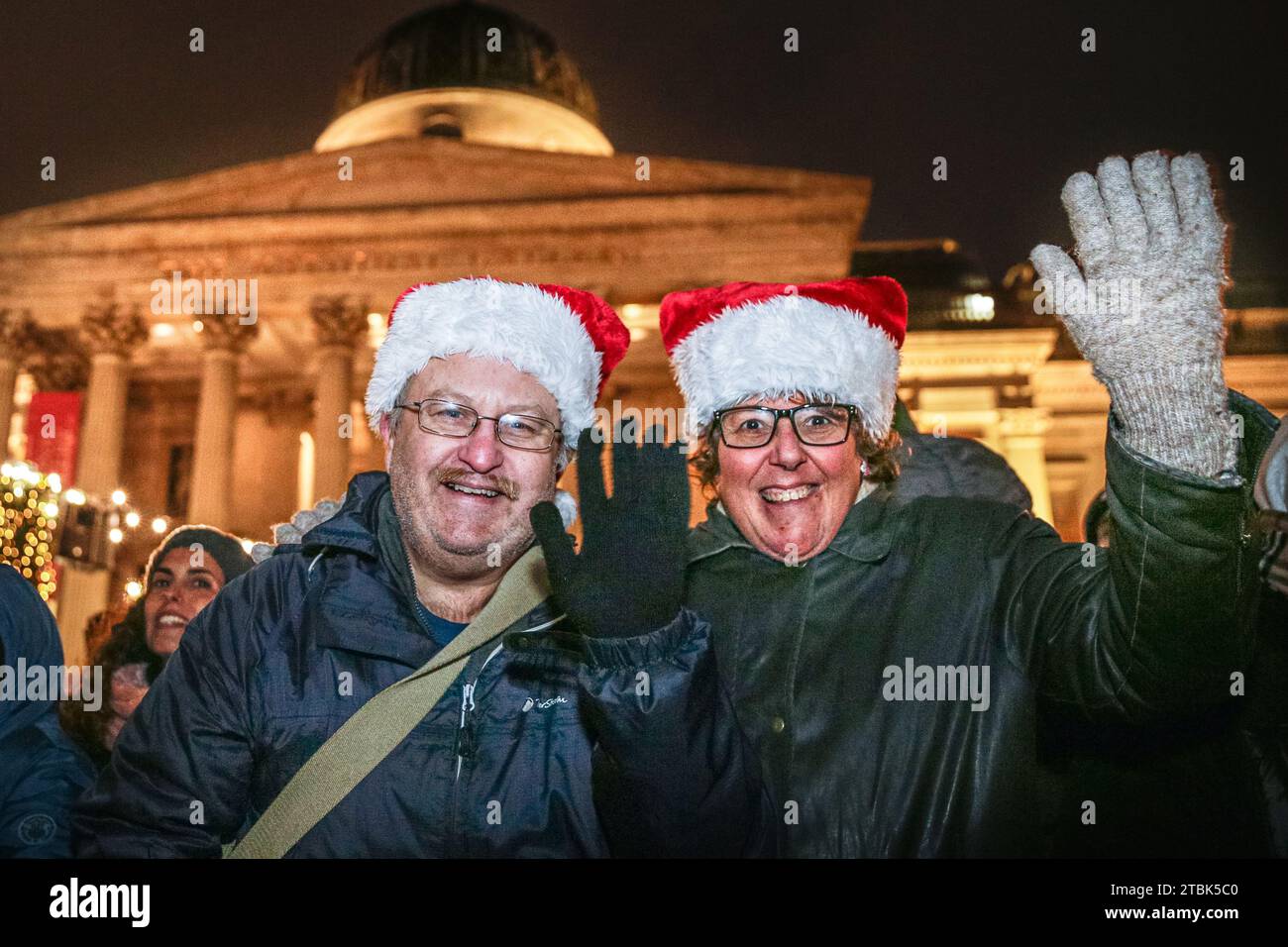 London, Großbritannien. Dezember 2023. Zwei Zuschauer sind warm eingewickelt und tragen Weihnachtsmützen. Die jährliche Zeremonie zum Einschalten des Weihnachtsbaums am Trafalgar Square sorgt für eine festliche Atmosphäre im Zentrum Londons, darunter Weihnachtslieder und Chorgesang. Jeden Dezember schickte ein Baum von Norwegen nach London als Geschenk, um Großbritannien für seine Unterstützung während des Zweiten Weltkriegs zu danken. In Anwesenheit von Patricia McAlliste, der Bürgermeisterin von Westminster, der Bürgermeisterin von Oslo Anne Lindboe, der Bürgermeisterin von London Sadiq Khan, der norwegischen Sängerin Metteson und anderen. Quelle: Imageplotter/Alamy Live News Stockfoto