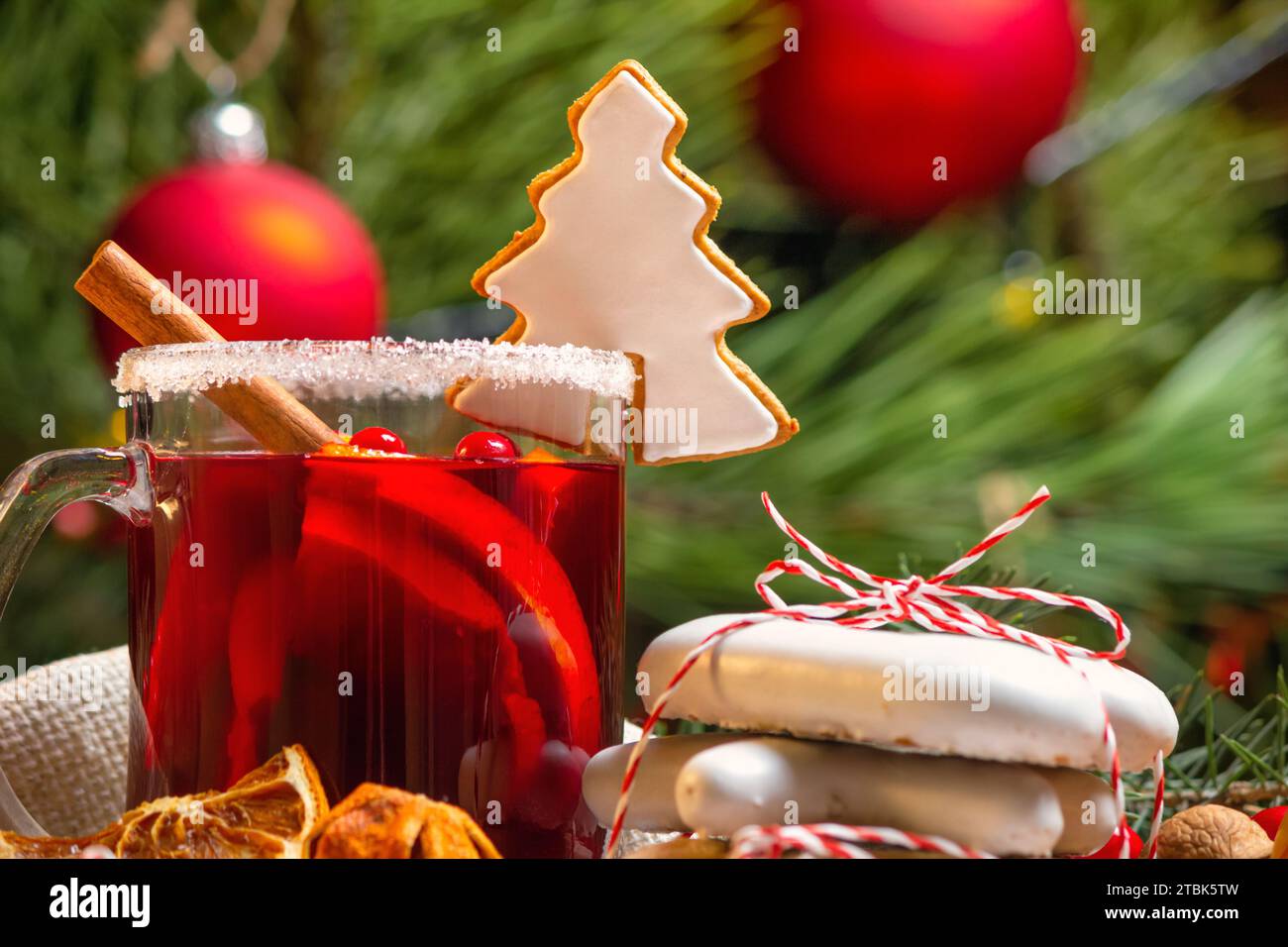 Weihnachtskonzert mit einer Tasse Glühwein und Weihnachtskeksen, Nahaufnahme mit selektivem Fokus auf den Hintergrund des Weihnachtsbaums Stockfoto