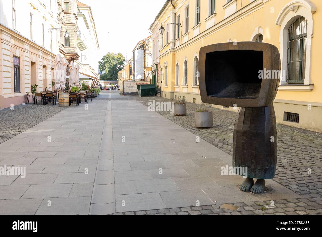 Eine Bronzestatue einer Frau, die einen Hut mit einem Fernsehgerät trägt, das in die Krone eingebettet ist, und auf weißem Hintergrund steht Stockfoto