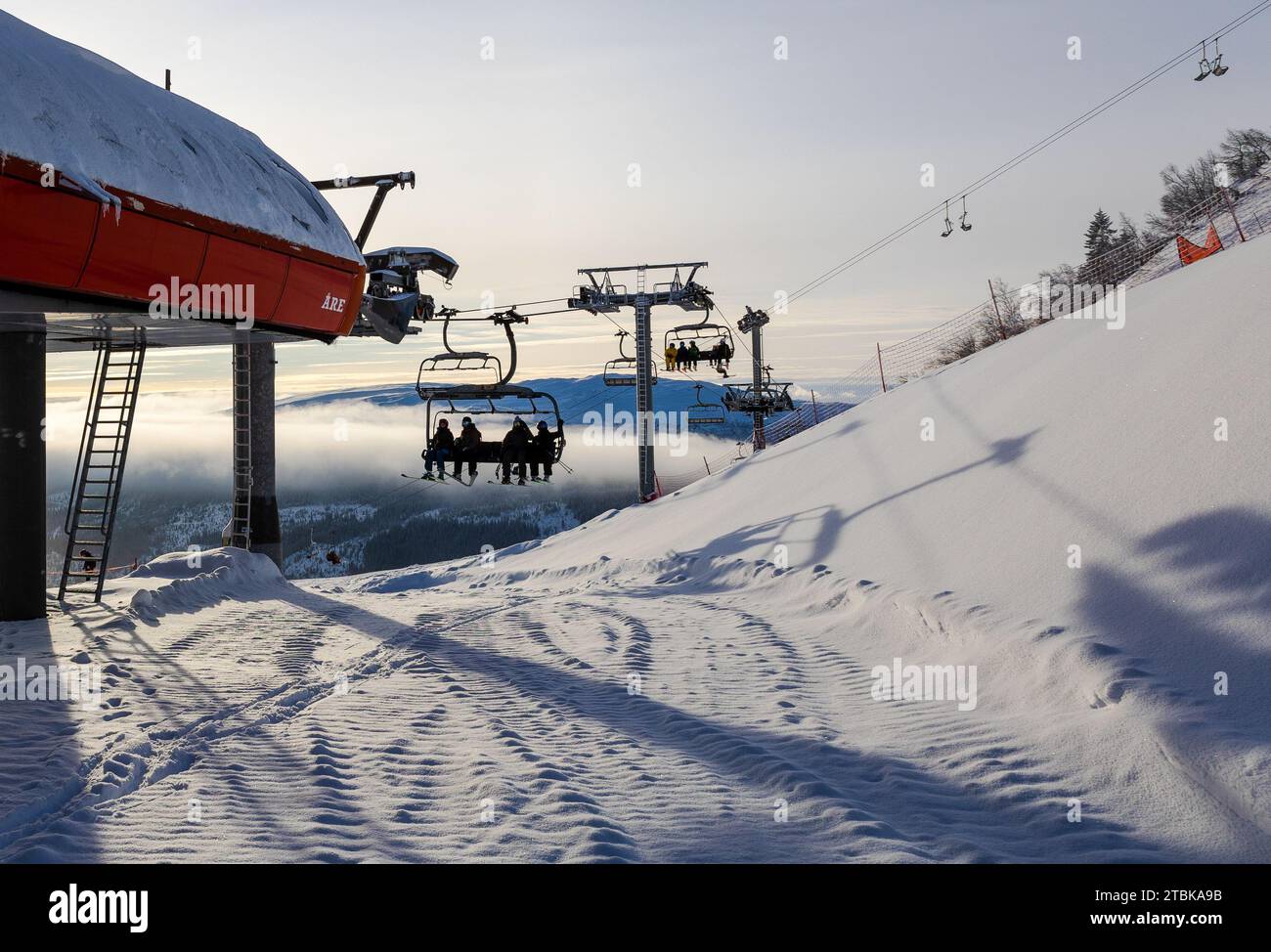 Eine Gruppe von Personen, die eine Fahrt mit dem Skilift genießen und einen schneebedeckten Hügel hinunterfahren Stockfoto