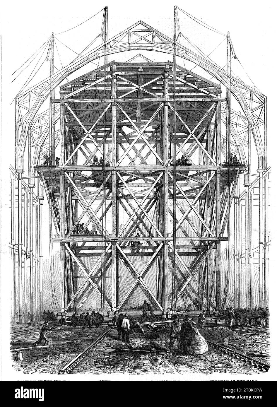 Fortschritt des großen Ausstellungsgebäudes: Die beim Bau des Kirchenschiffs verwendete Traversionsplattform, 1861. "...das erstaunlichste und umfangreichste der arbeitssparenden Arbeiten ist ein gigantisches Wandergerüst, das auf zwölf Rädern gebaut wurde und auf Schienen über die gesamte Länge des Mittelschiffs hinauf und hinunter läuft. Dieses riesige Gebäude ist 60 Fuß groß. Quadratisch und 100 ft. Hoch und wiegt fast 300 Tonnen. Aber... vier Männer mit Hebeln können es mit einer gewissen Geschwindigkeit auf jeden Teil der Werke bewegen. Sie wird zum Heben der oberen Säulen, der riesigen runden Holzrippen des verwendet Stockfoto