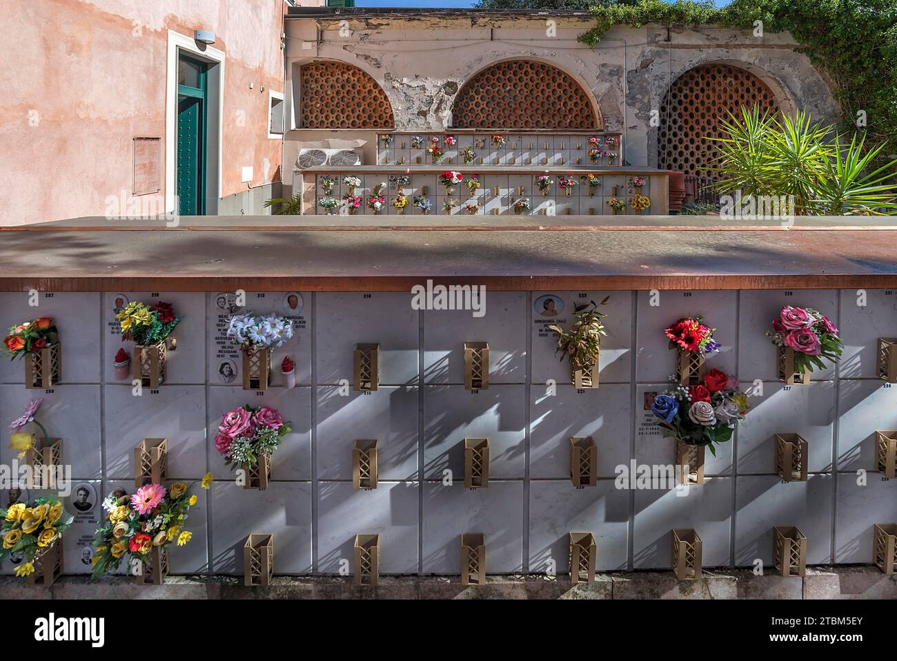 Mit Blumen geschmückte Urnengräber in einem Innenhof, Monumentalfriedhof, Cimitero monumentale di Staglieno), Genua, Italien Stockfoto