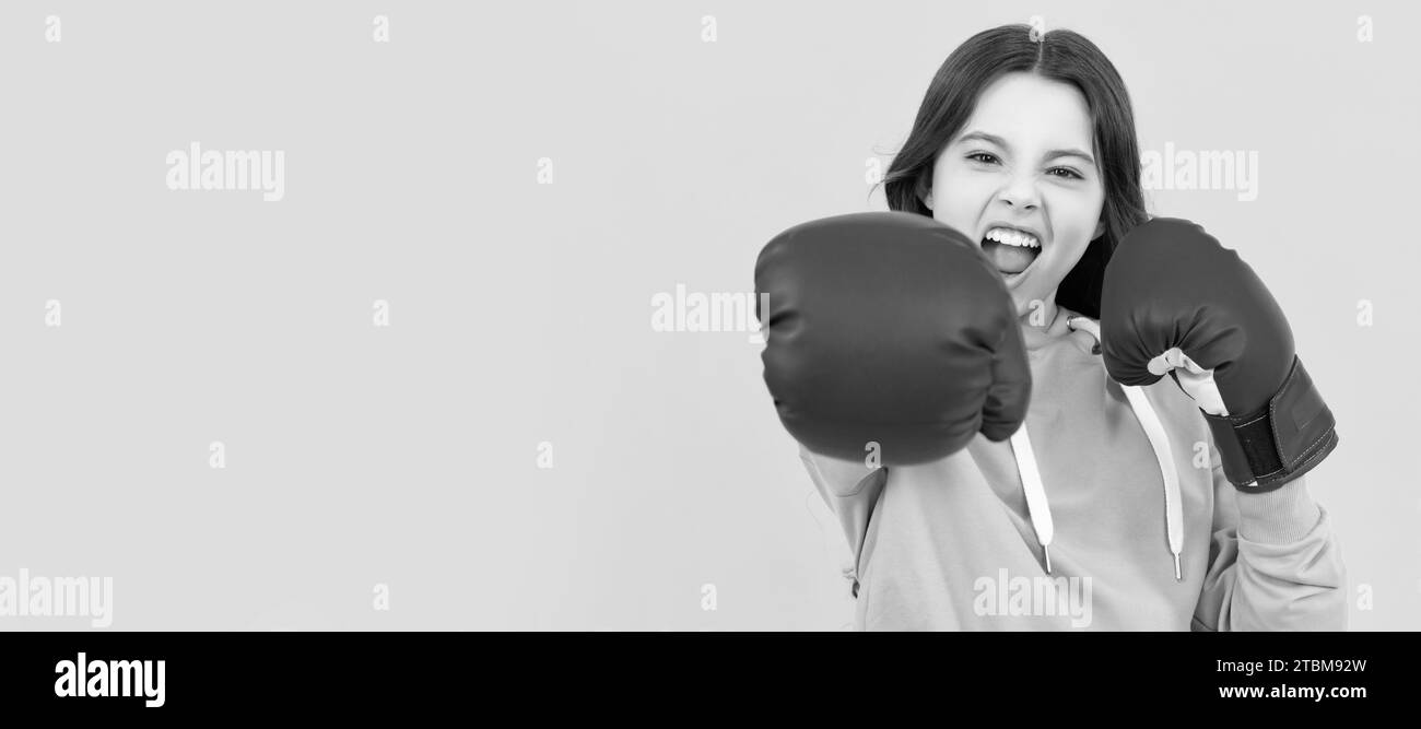 Aggressives Kinderstanzen in Boxhandschuhen auf gelbem Hintergrund, Sport. Horizontales Poster mit isoliertem Kindergesicht, Banner-Header, Kopierbereich. Stockfoto