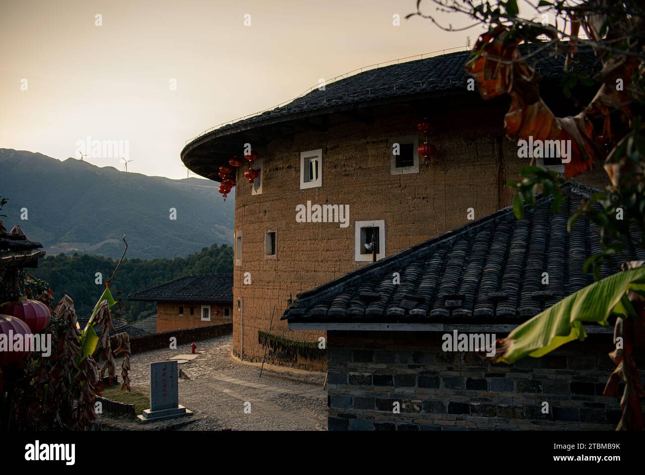 Chinesisches Fujian Tulou und die umliegende Landschaft während des Sonnenuntergangs. Es wurde zum UNESCO-Weltkulturerbe erklärt. Ein berühmtes historisches Relikt. Stockfoto Chinesisches Fujian Tulou und die umliegende Landschaft während des Sonnenuntergangs. Es wurde zum UNESCO-Weltkulturerbe erklärt. Ein berühmtes historisches Relikt. Stockfoto