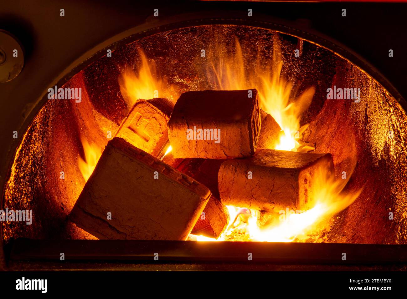 Holzbriketts (ruf-Typ) aus Buche und Eiche, die im Brennstoffkessel verbrennen. Alternativer Kraftstoff, Öko-Kraftstoff, Biokraftstoff Stockfoto