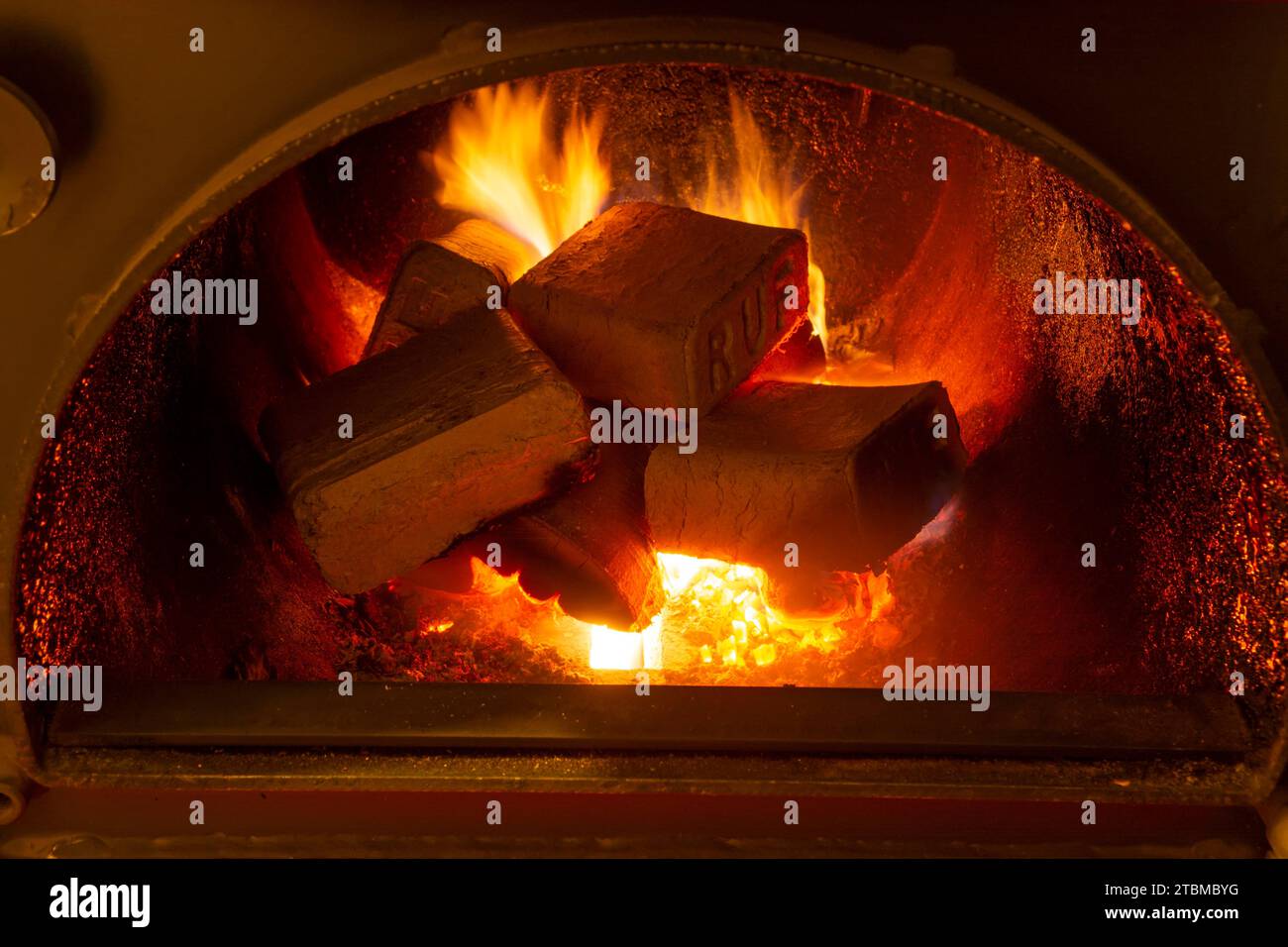 Holzbriketts (ruf-Typ) aus Buche und Eiche, die im Brennstoffkessel verbrennen. Alternativer Kraftstoff, Öko-Kraftstoff, Biokraftstoff Stockfoto