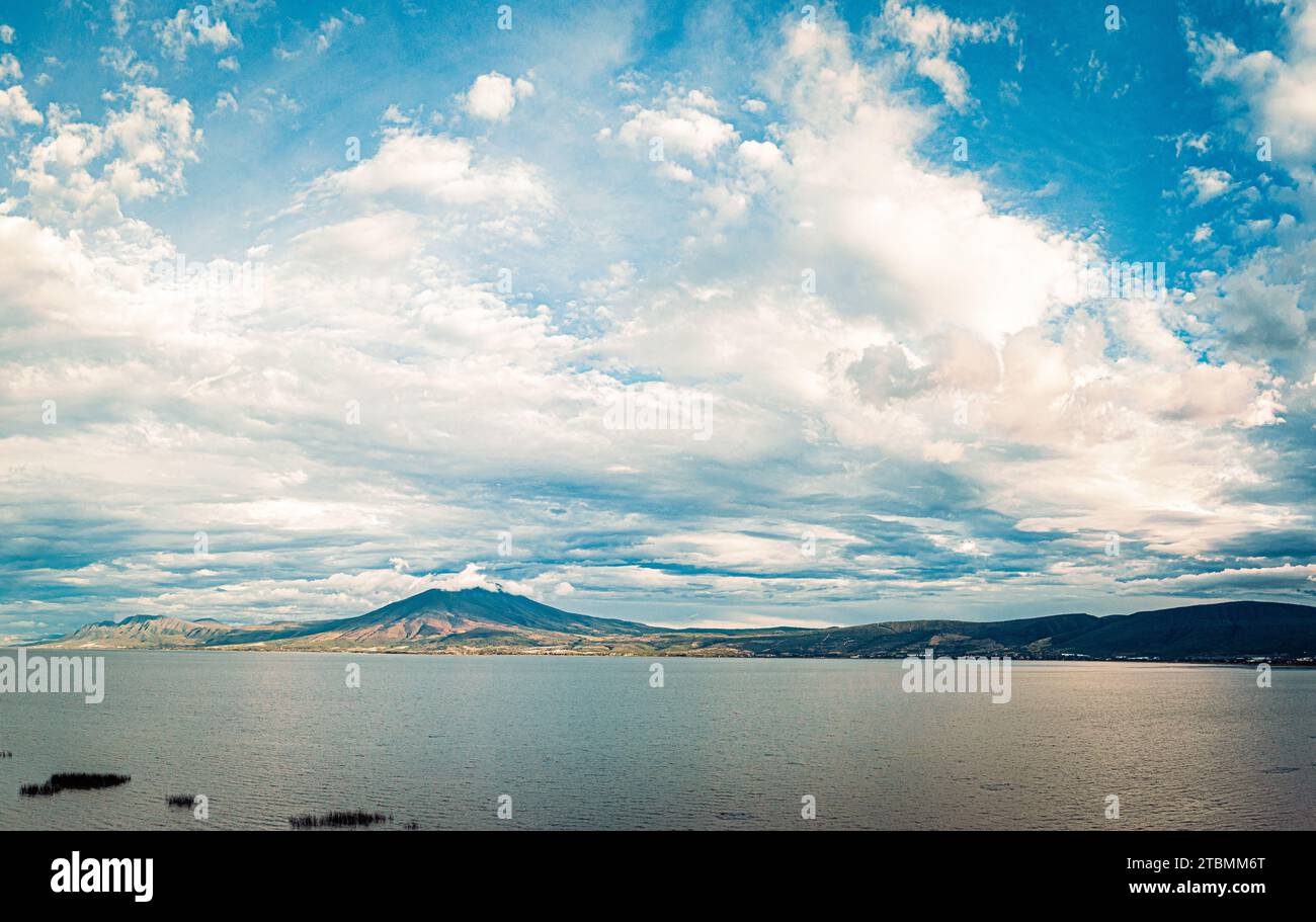 Ein blauer Himmel über einem Berg neben einem See mit Wolken und wunderschönem Panorama Stockfoto