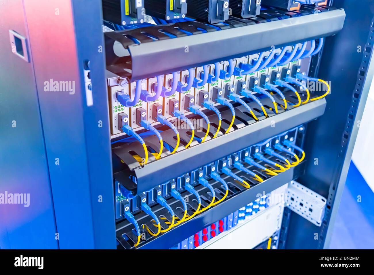 Glasfaserkabel, die an optische Ports angeschlossen sind, und Netzwerkkabel, die an ethernet-Ports angeschlossen sind. Stockfoto