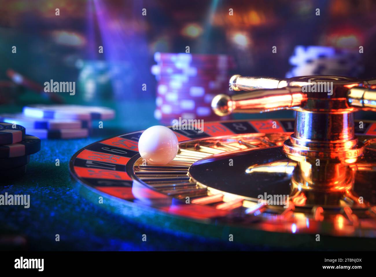 Detail eines festen Balls auf einer Casino-Roulette-Nummer auf einer Spielmatte mit Wettchips und Lichtern in einem dunklen Spielzimmer Stockfoto