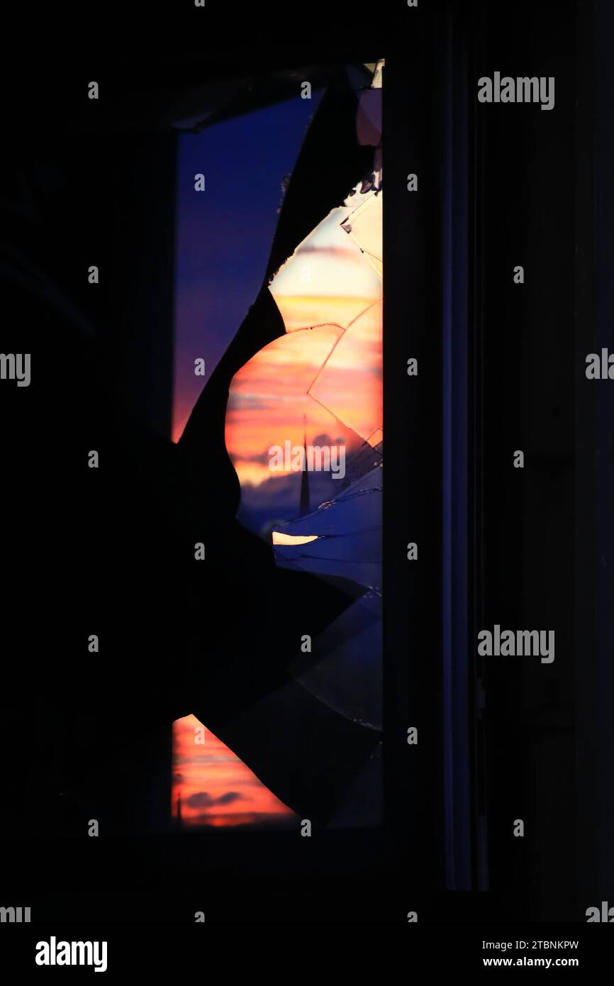 Wunderschöner Sonnenuntergangshimmel, der sich in Glassplittern eines kaputten Fensters spiegelt. Stockfoto