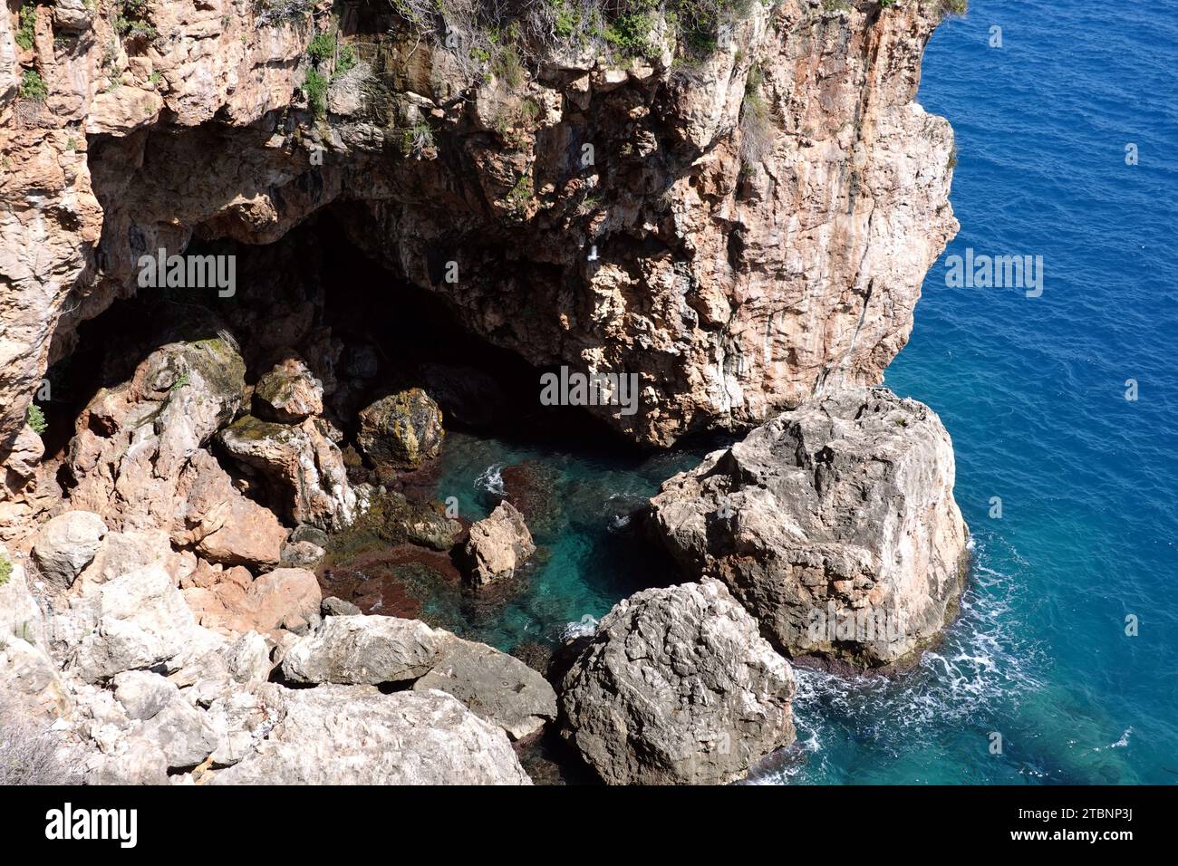 Blick von oben auf Steingrotte und azurblaue Wasseroberfläche auf dem Meer mit kleinen Wellen an sonnigen Tagen Stockfoto