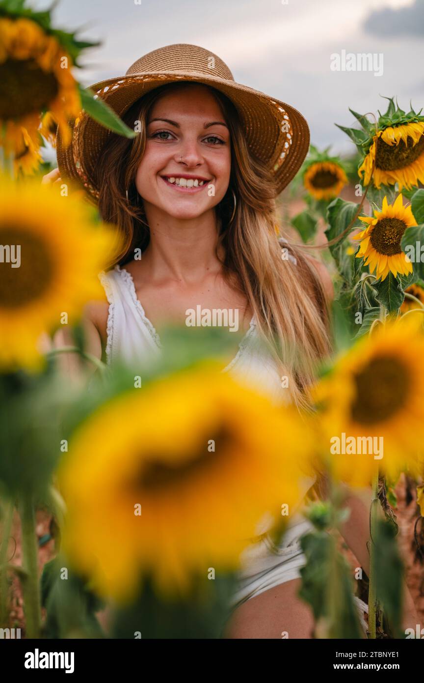 Porträt einer blonden Frau mit Hut umgeben von Sonnenblumen. Stockfoto