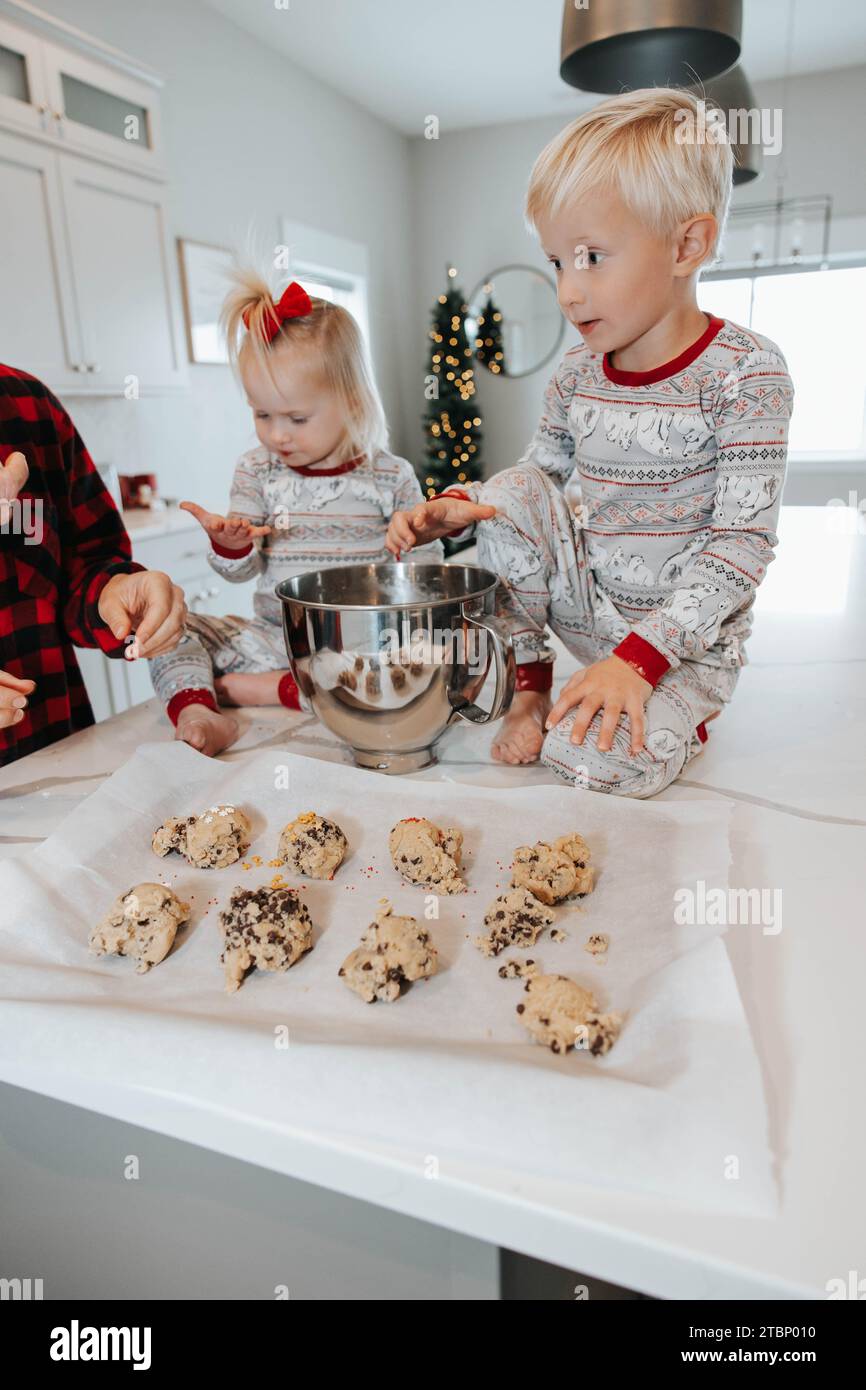 Kinder helfen, Kekse mit Weihnachtsstreuseln zu dekorieren Stockfoto