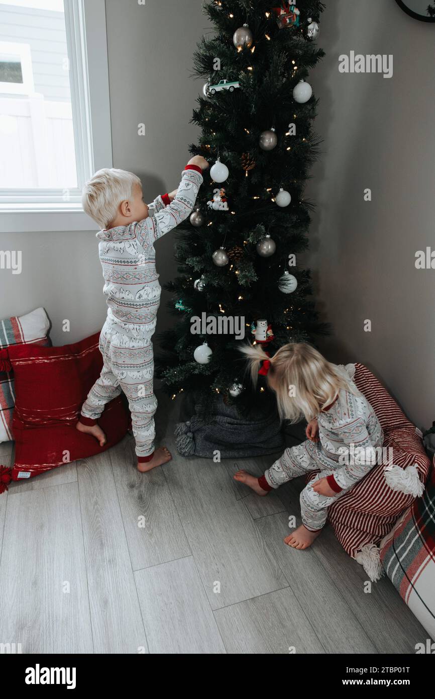 Kinder schmücken den Baum mit Weihnachtsfreude Stockfoto
