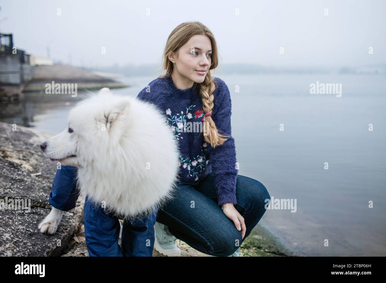 Ein Mädchen läuft mit einem weißen, flauschigen Samoidenhund in der Natur Stockfoto