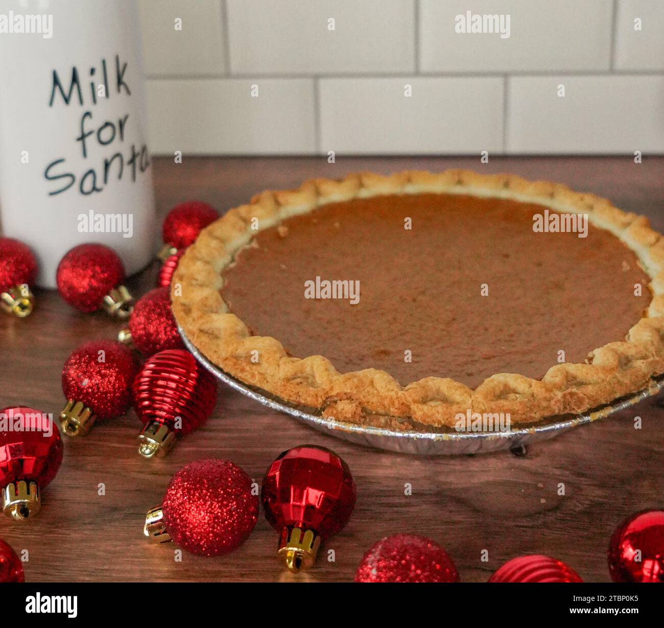 Kürbiskuchen, Flasche Milch für den weihnachtsmann, umgeben von roten Ornamenten Stockfoto