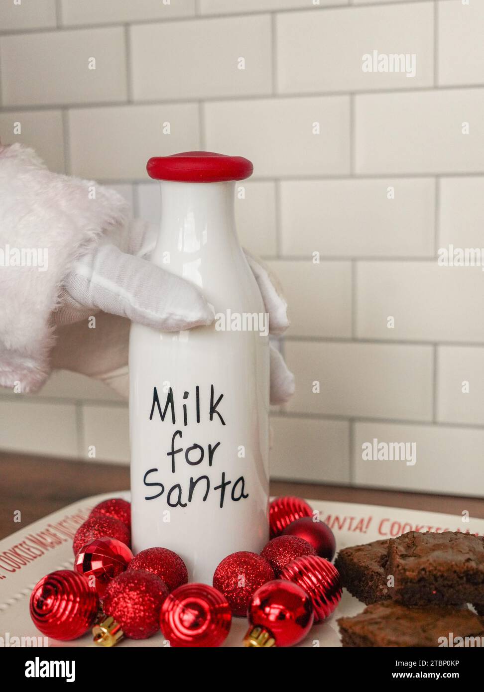 Der Weihnachtsmann greift nach einer Flasche Milch neben Brownies Stockfoto