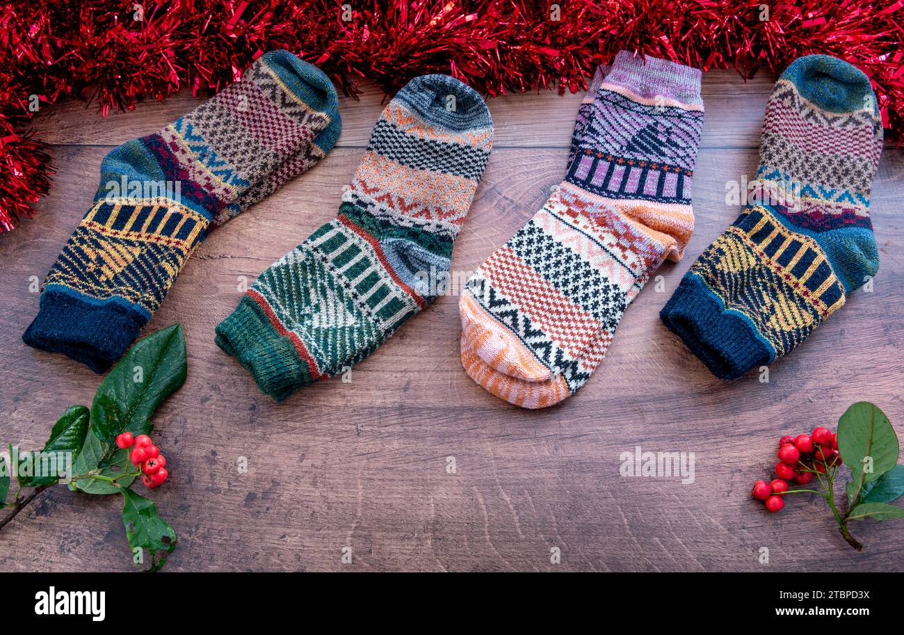 Farbenfrohe Wintersocken aus Wolle mit Weihnachtsdekoration und Winterbeeren auf Holzhintergrund. Stockfoto