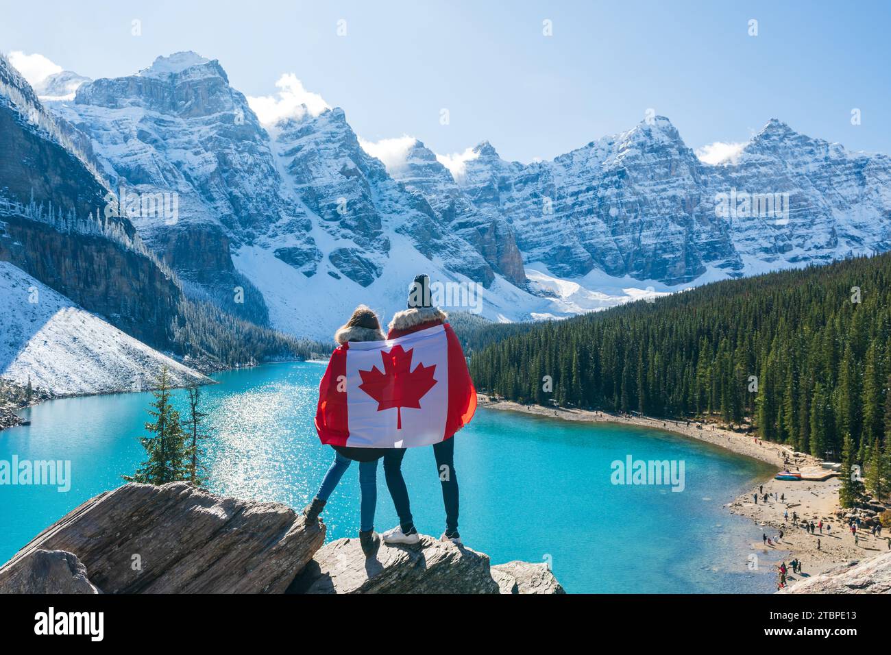 Touristen, die in kanadischer Flagge gehüllt sind und eine wunderschöne Landschaft des Moraine Sees sehen. Banff National Park. Kanadische Rockies. Alberta, Kanada. Stockfoto