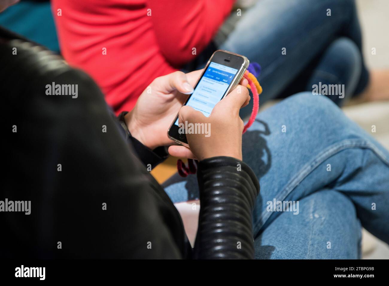 Im Glanz eines mobilen Bildschirms zeigt der Rücken einer Frau die Interaktion mit einer App und verkörpert moderne Konnektivität und nahtlose digitale Inhalte Stockfoto