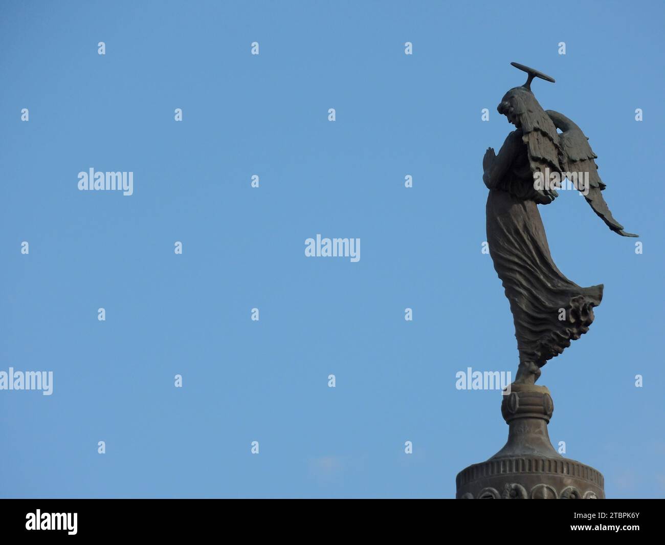 Eine Bronzestatue einer Figur mit einem Hammer in der Hand, die auf einem hohen Gebäude steht Stockfoto
