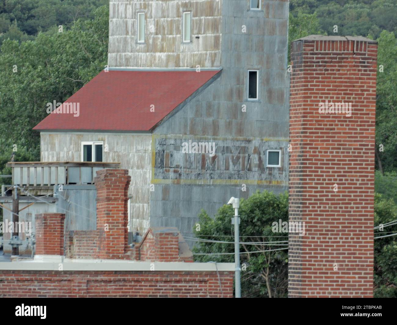 Seitenansicht eines hohen Zementsilo neben zwei Backsteinpfeilern und einer kleinen Kapelle Stockfoto