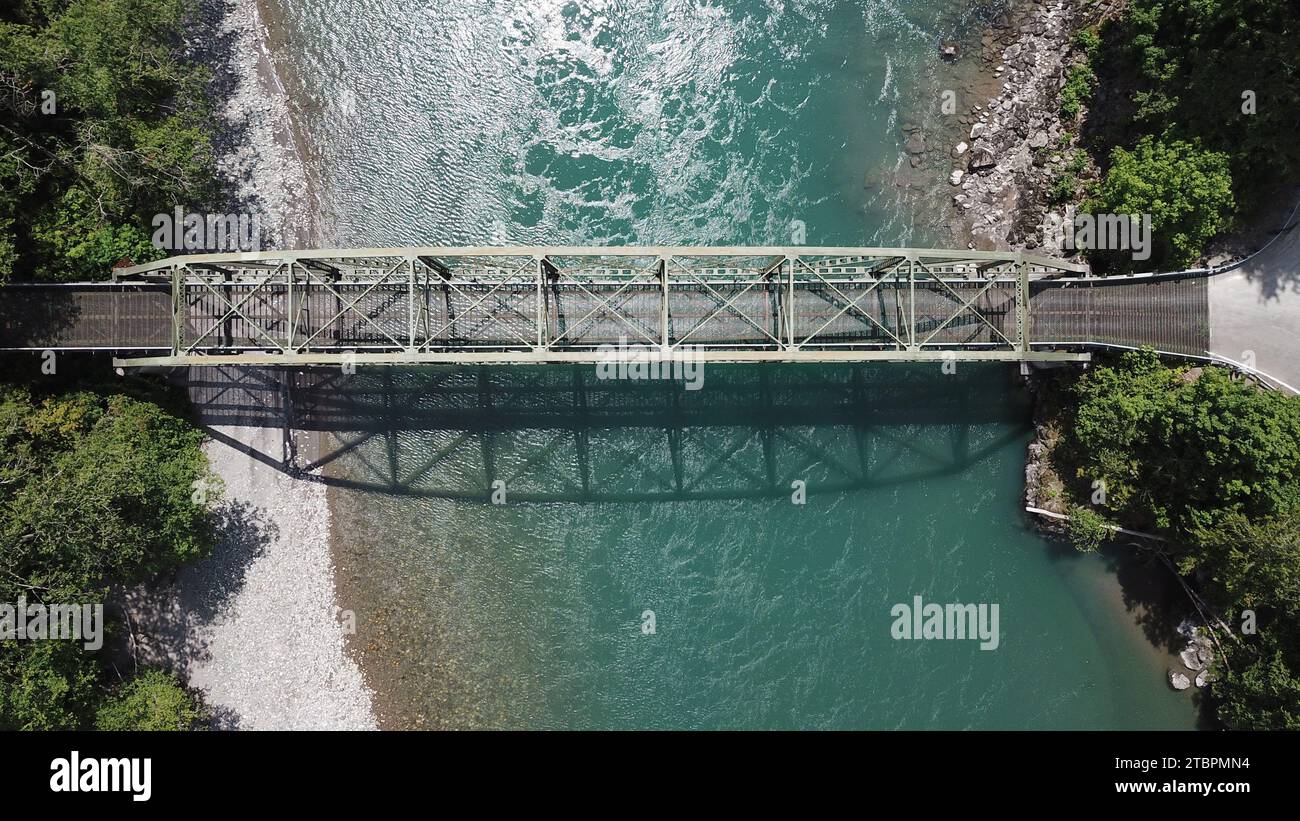 Ein malerischer Blick auf eine lange Brücke über einen Fluss mit üppigen grünen Bäumen und Gras im Hintergrund Stockfoto