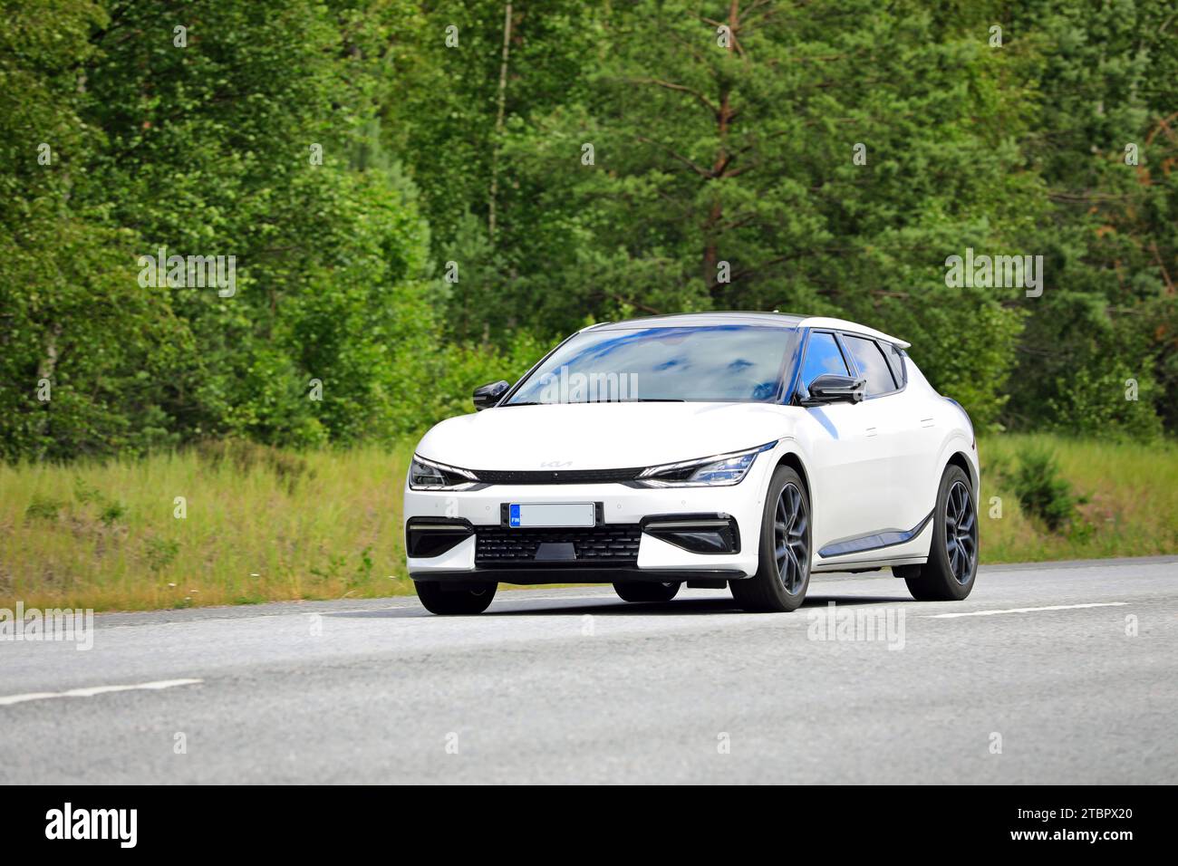 Weißes Kia EV6 vollelektrisches Auto bei Geschwindigkeit auf der Autobahn, grüner Waldhintergrund. Raasepori, Finnland. Juli 2023. Stockfoto