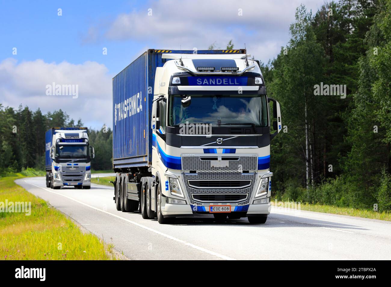 Zwei blau-weiße Volvo FH-Sattelzüge der Kuljetusliike H Sandell Oy transportieren Frachtcontainer entlang der Autobahn 25. Raasepori, Finnland. Juli 2023. Stockfoto