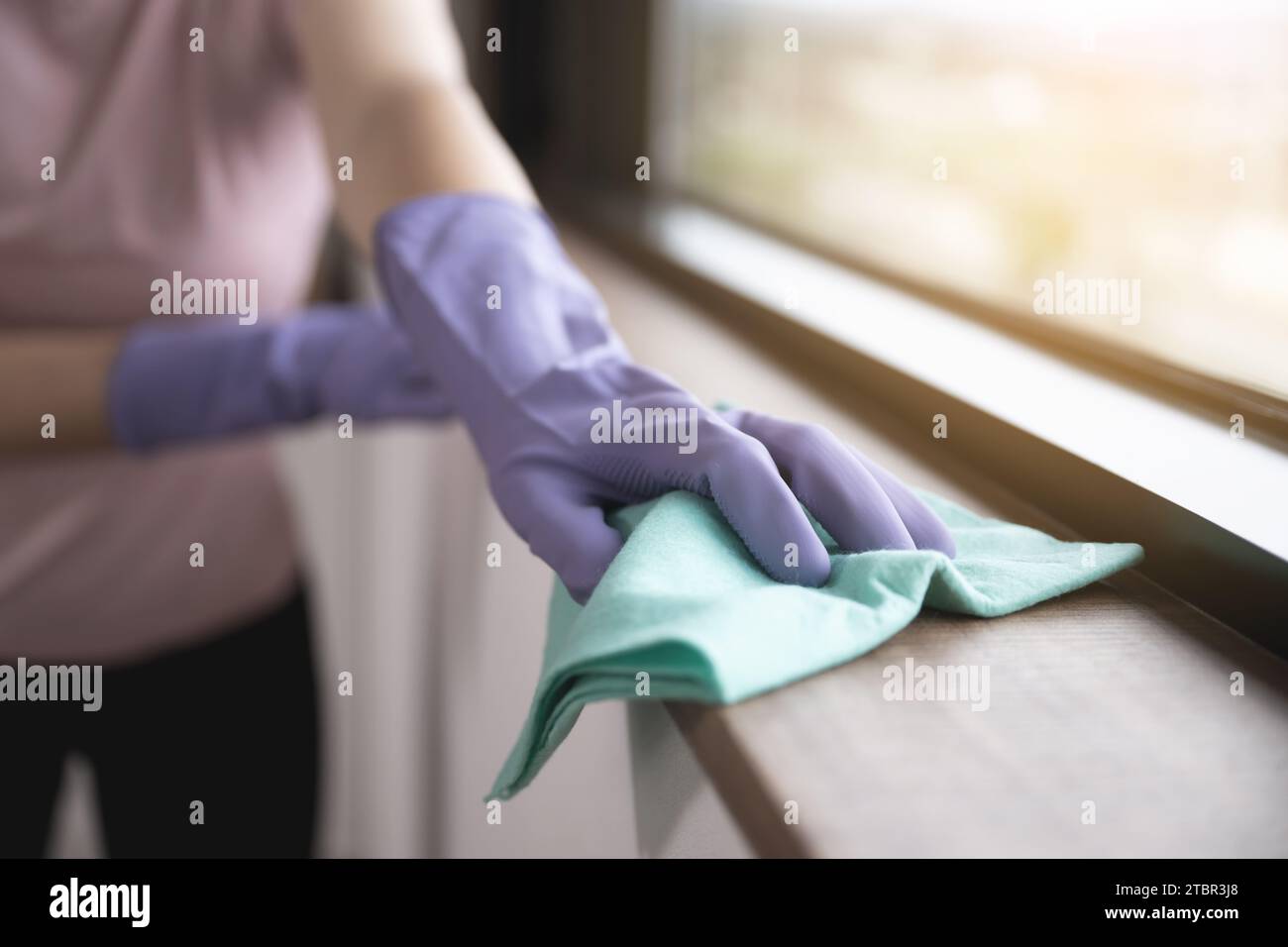 Die Hand der Frau wischt die Fensterbank Stockfoto